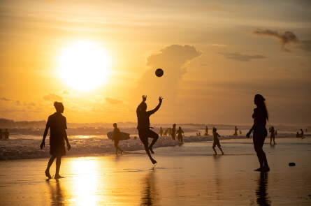 Group Of People Playing Beach ball in sunset.