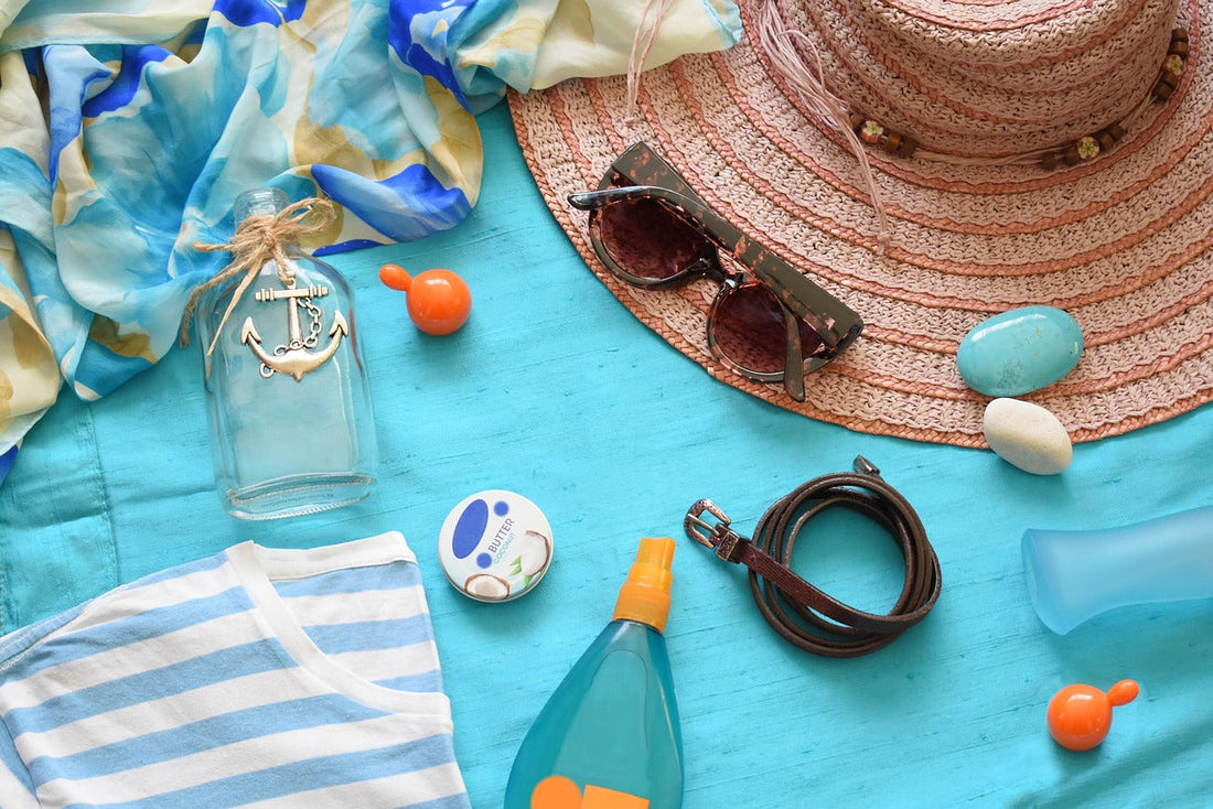 A beach scene with a cloth spread on sand, sunglasses, sunscreen, and other beach essentials, highlighting sun protection.