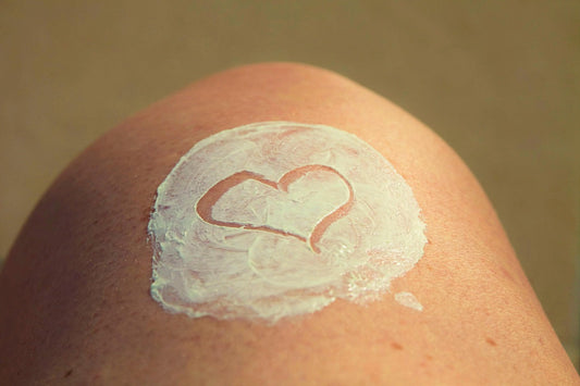 Close-up of a knee with sunscreen applied in the shape of a heart, representing the importance of sun safety.